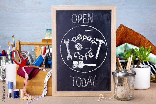 Repair cafe sign on chalk board on table with tools and fabric, the right to repair consumer goods to reduce waste for sustainable living photo