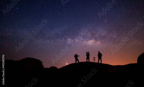 Teamwork and support. A group of people is standing together, beautiful, wide blue night sky with stars and Milky way galaxy. Astronomy, orientation, clear sky concept, and background.