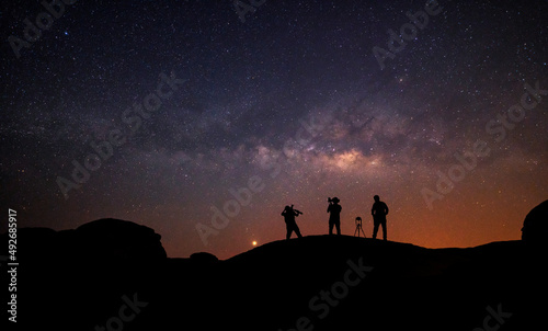 Teamwork and support. A group of people is standing together  beautiful  wide blue night sky with stars and Milky way galaxy. Astronomy  orientation  clear sky concept  and background.