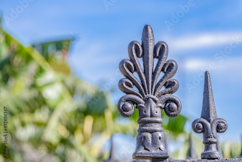 Close up of a fleur de lis made of iron, part of the gate in Jackson Square in the French Quarter, in New Orleans. Shallow focus on the large fleur de lis for artistic effect.