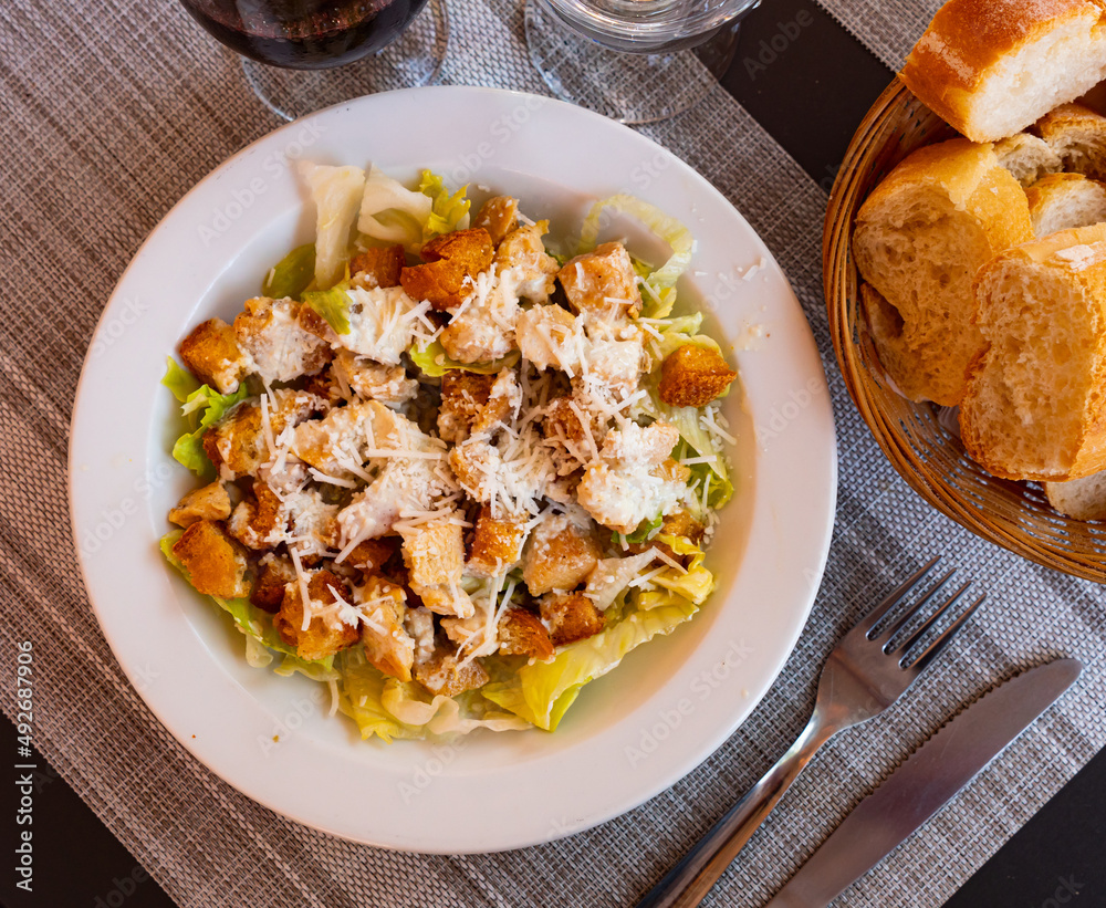 Traditional Caesar salad with chicken, parmesan and wheat croutons on a ceramic plate