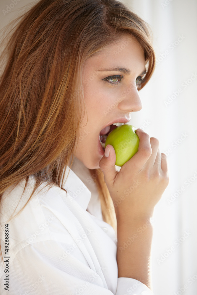 Biting into a juicy green apple. A beautiful young woman biting into a delicious apple. Biting into a juicy green apple. A beautiful young woman biting into a delicious apple.