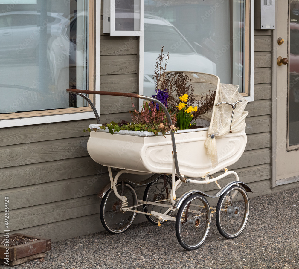 Vintage Pram Baby. Baby stroller decorated with flowers. Vintage baby stroller in beautiful interior with decoration.