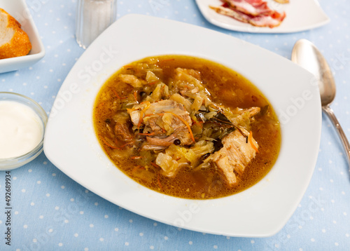 Soup of cabbage Shchi with pork and vegetables, served in bowl