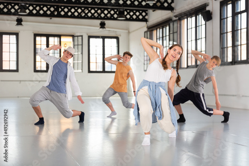 Group of teenagers training at dance class, practicing hip hop moves