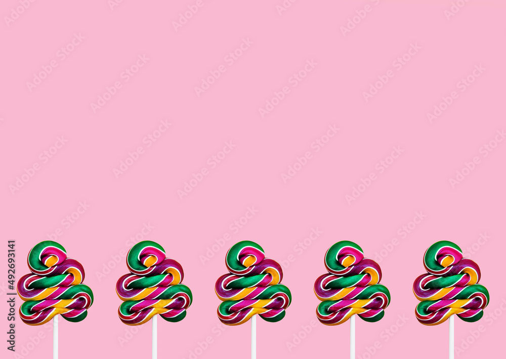 Sweet swirl lollipops. Top view photo with copy space. Colorful striped candies on sticks on pink backdrop