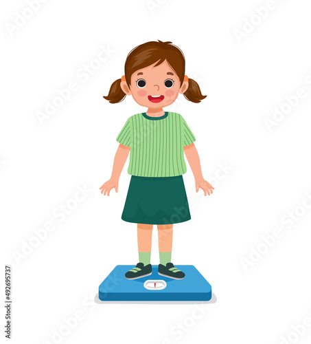 happy little girl child standing on the weighing scale checking her weight