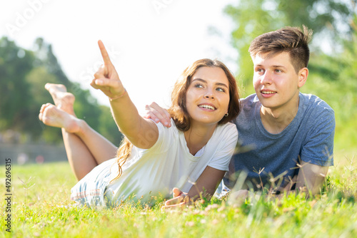 A couple of young people is lying on the grass