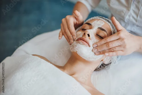 Obraz Close-up portrait of anorganic facial mask application at spa salon. Facial treatment. Skin care. Health care. Rejuvenation treatment.