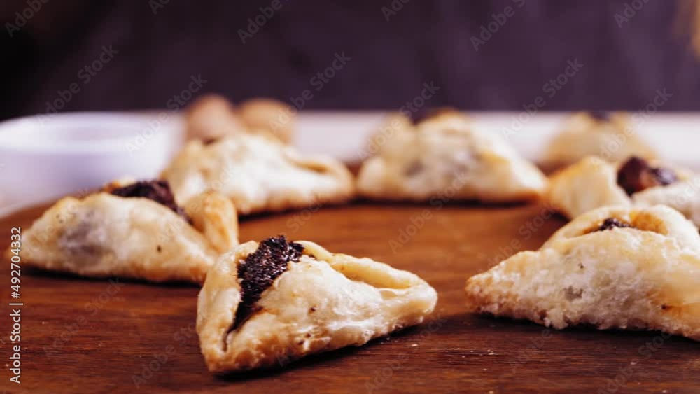Purim cookies with poppy-seed filling triangular gomentashi rotate in a circle on a wooden board. Purim cookies with poppy-seed filling triangular gomentashi rotate in a circle on a wooden board.