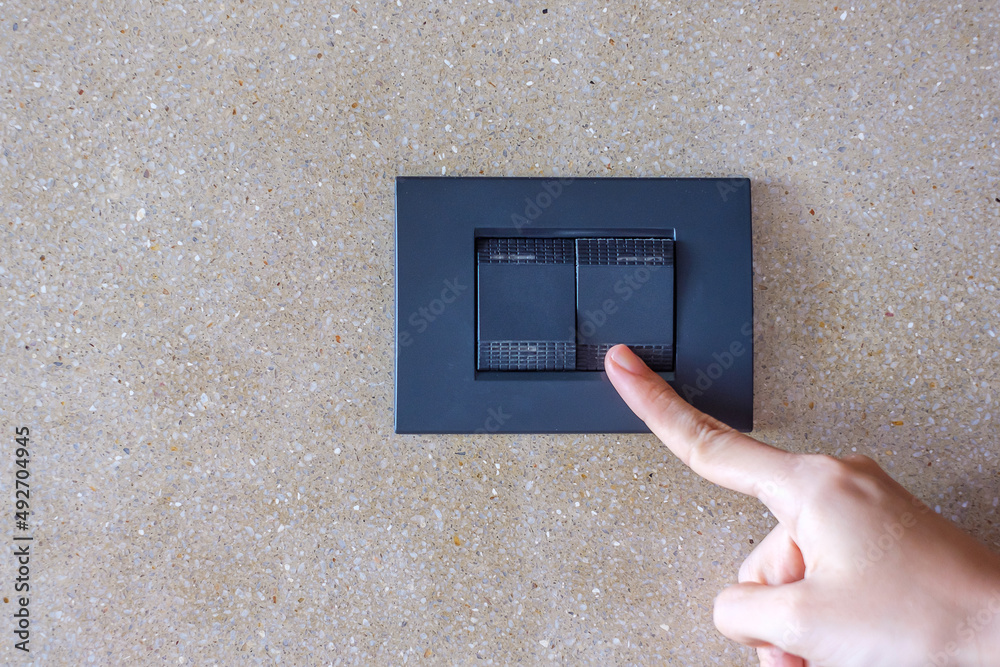 finger turn on or off on light switch on wall at home. Energy Saving