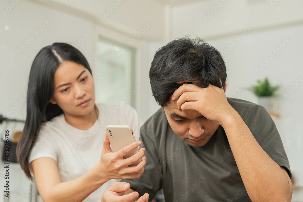 Infidelity, suspicion asian young couple love fight relationship, wife holding cellphone, smartphone cheating on phone, scolding husband about mistrust, distrust and jealousy when sitting at home. Infidelity, suspicion asian young couple love fight relationship, wife holding cellphone, smartphone cheating on phone, scolding husband about mistrust, distrust and jealousy when sitting at home.