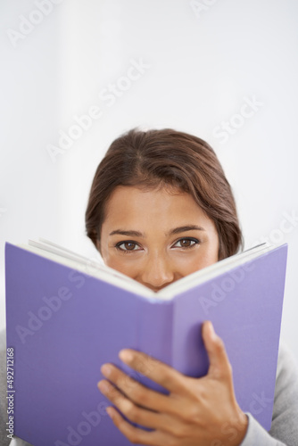 This is an interesting read. Close up shot of a smiling, young woman reading her book.