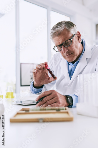Its easier to log detailed observations with technology. Shot of a mature scientist analyzing a test tube while using a digital tablet in a lab.