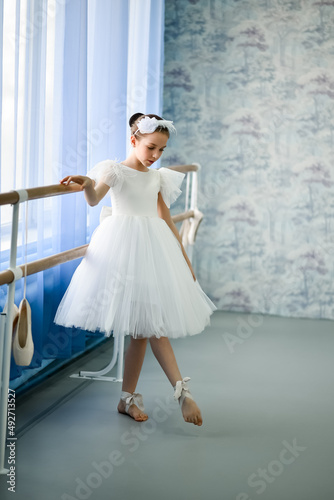 A beautiful girl ballerina in a white dress is engaged at the stonk. She's in a dance studio. Beauty. Dancing. Creation.