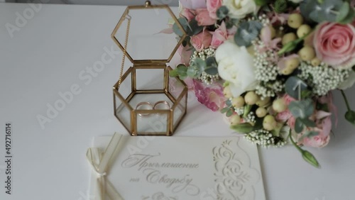 rings of the newlyweds in a transparent box, the bride's wedding bouquet and wedding invitations