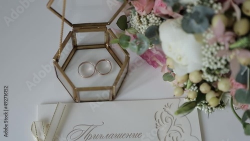 wedding rings in a transparent box, a wedding bouquet and an invitation to a wedding in daylight