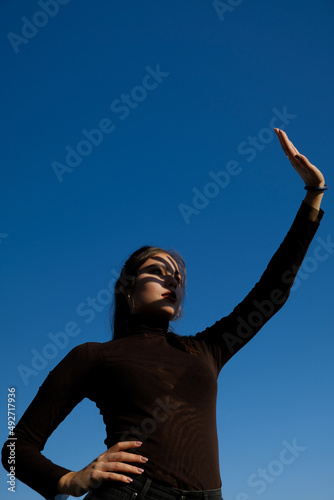 woman with arm outstretched against the sun on a blue sky background
