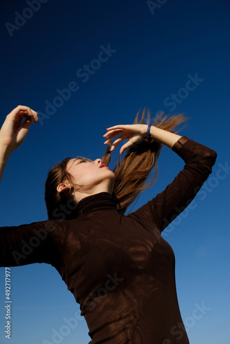 a female with arms outstretched and loosen long hair against blue sky