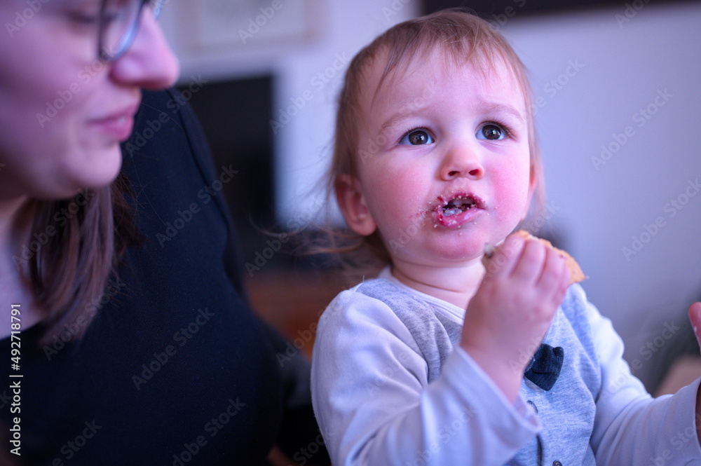 Mother holding her cute little boy who is eating cookie Mother holding her cute little boy who is eating cookie