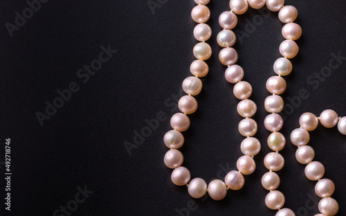 Pink pearl luxury necklace with beautiful nacreous real oyster pearl beads isolated on black background with copy space