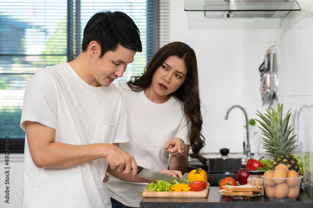 tired couple cooking and preparing vegetables in kitchen at home, angry woman pointing hand to man tired couple cooking and preparing vegetables in kitchen at home, angry woman pointing hand to man