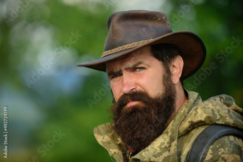 Portrait of handsome bearded man with serious face ond cowboy hat outdoor. Close up masculine face.