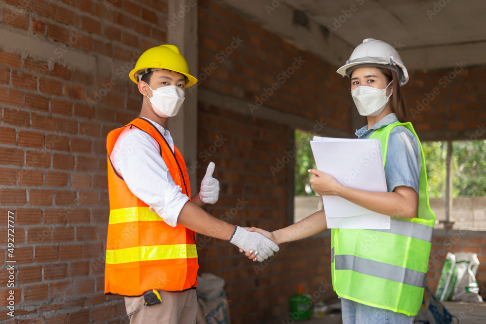 engineer concept The male engineering worker who wears oranges uniform shaking hand with the female worker who wears green uniform