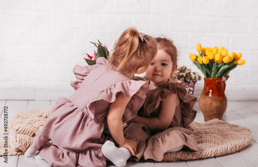two little girls in beautifull dresses at the studio with flowers two little girls in beautifull dresses at the studio with flowers