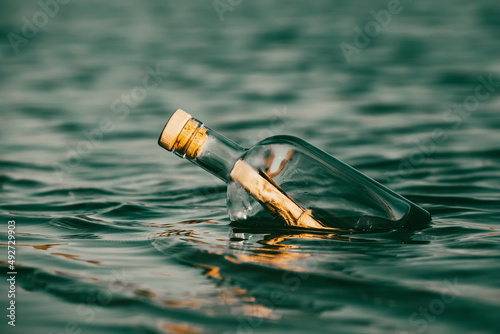 Message in a bottle floating on the ocean waves. Calling for help. photo