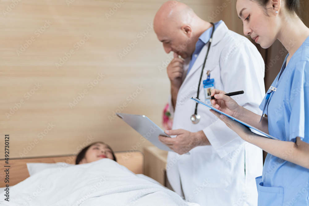 Doctor and medical student examining patient lying in bed Doctor and medical student examining patient lying in bed