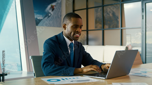 Young man in a suit typing on a laptop