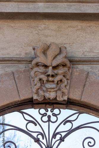 closeup shot of male mascaron - exterior details of a gate with wrought iron decorations