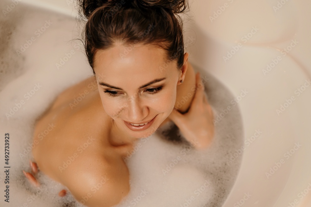 Close up relaxed woman lying in bath foam at bathroom. Romantic girl relaxing at bathtub at home. Close up sexy woman taking bath indoors. Close up relaxed woman lying in bath foam at bathroom. Romantic girl relaxing at bathtub at home. Close up sexy woman taking bath indoors.