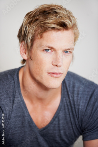 Eyes like a hawk. Portrait of a handsome young man sitting against a grey background.