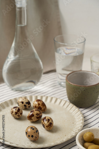Set wish glass bottle, glass and small quail eggs on the table. 