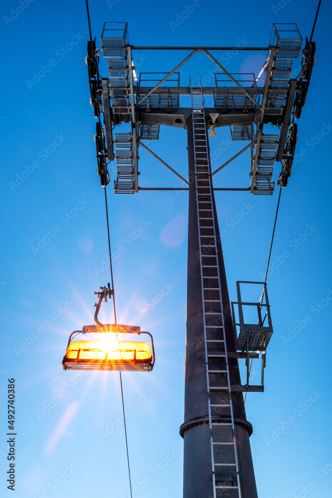 Fototapeta premium Empty ski-lift chair and cable car mast