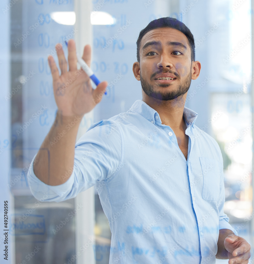He always has a plan to follow. Shot of a young businessman writing notes on a glass wall in an office. He always has a plan to follow. Shot of a young businessman writing notes on a glass wall in an office.