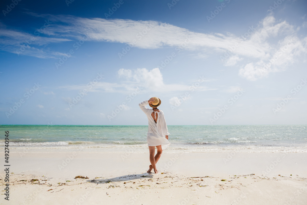 Happy traveller woman in white dress and hat enjoys her tropical beach vacation Happy traveller woman in white dress and hat enjoys her tropical beach vacation