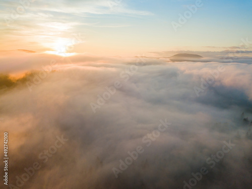 The rays of dawn over the fog in the Ukrainian Carpathians. Aerial drone view.