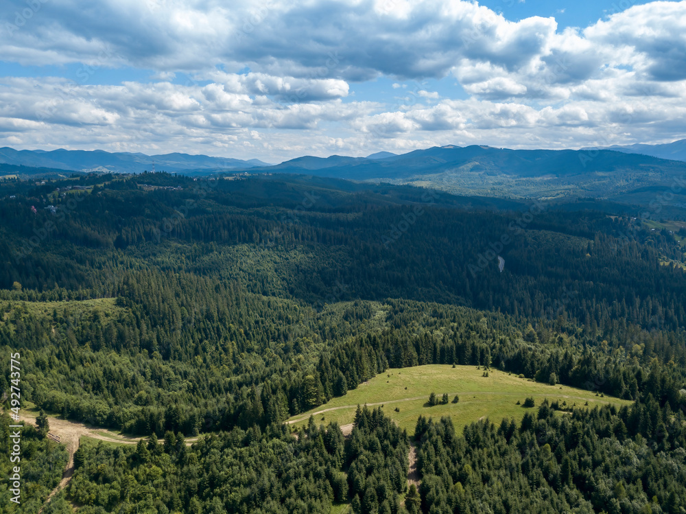 Green mountains of Ukrainian Carpathians in summer. Coniferous trees on the slopes. Aerial drone view.