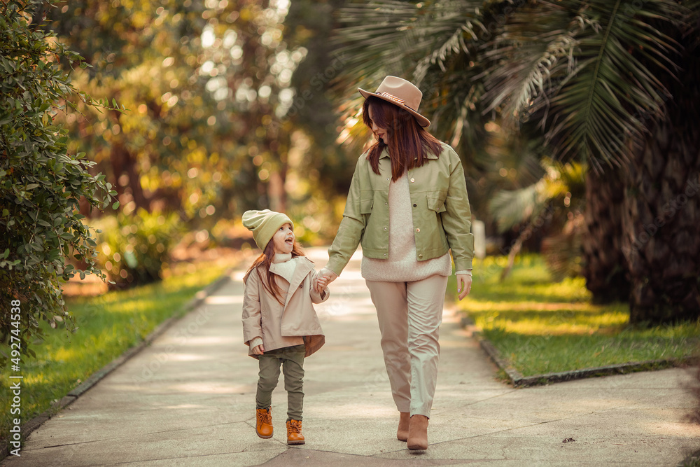 Fototapeta premium red-haired mother and daughter are walking in the park. family leisure in the city