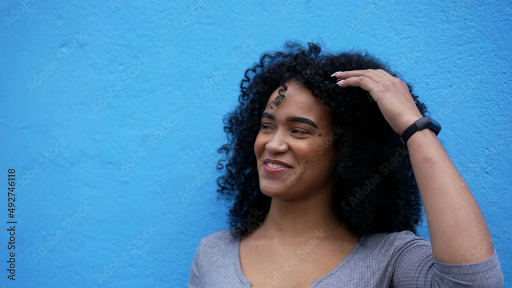 A fun loving young woman leaning on blue wall laughing and smiling A fun loving young woman leaning on blue wall laughing and smiling