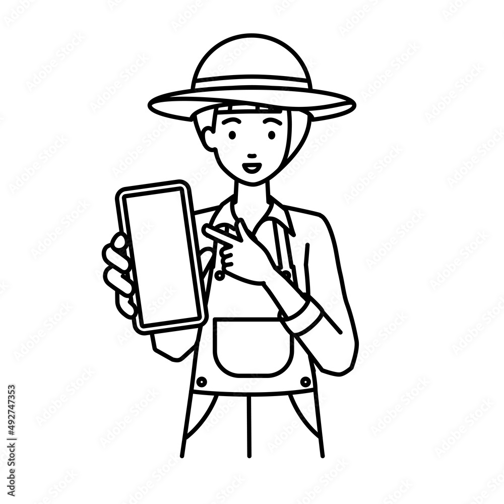 立ってスマートフォンを指差してこちらに向けて見せている農家の女性 立ってスマートフォンを指差してこちらに向けて見せている農家の女性