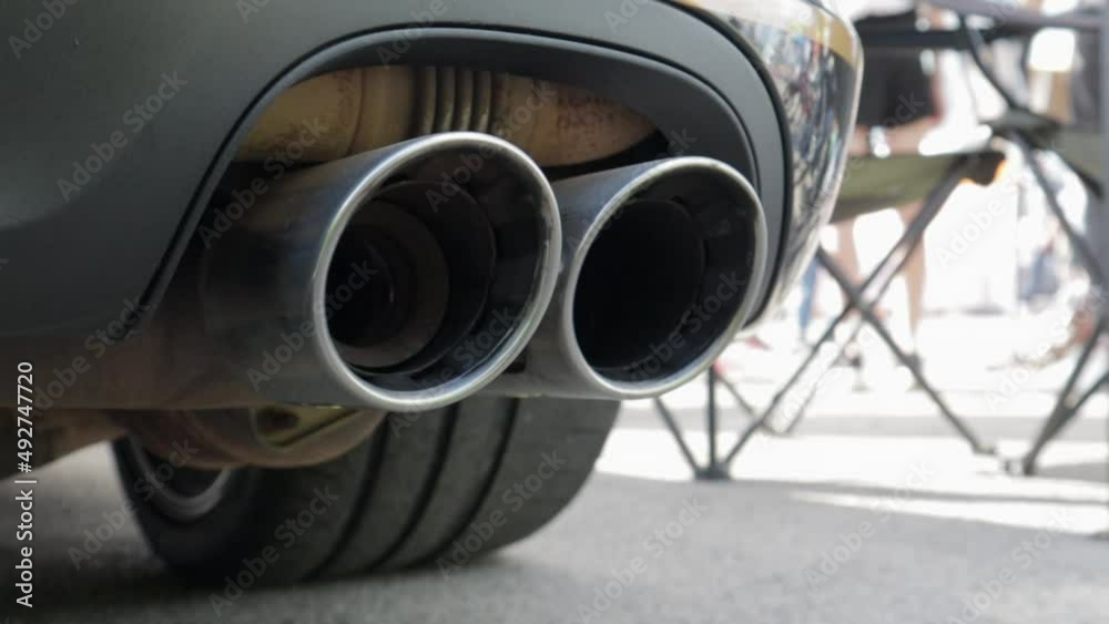 Bottom view of the exhaust system of a new luxury car. Panoramic view. Close-up of a dual exhaust pipe to remove harmful substances from engine exhaust and reduce vehicle noise.