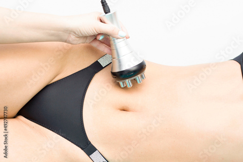 procedure removing cellulite on female abdomen, cavitation belly massage. Ultrasonic massage for weight loss. Correction of female figure without surgical intervention. Closeup of the tummy. photo