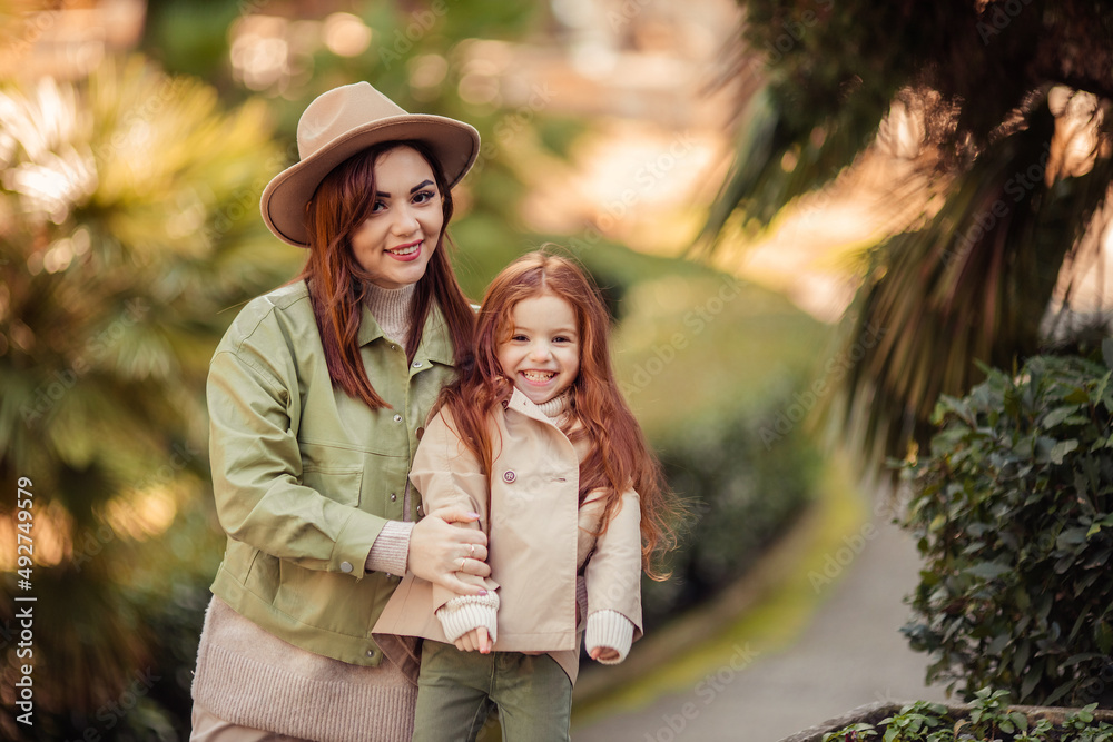 Fototapeta premium red-haired mother and daughter are walking in the park. family leisure in the city
