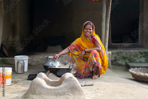 Rural Indian Woman cooking food in the Kitchen using firewood stove photo