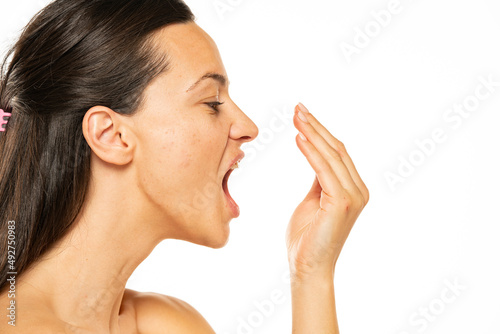 Beuatiful young woman checks her breath on a white