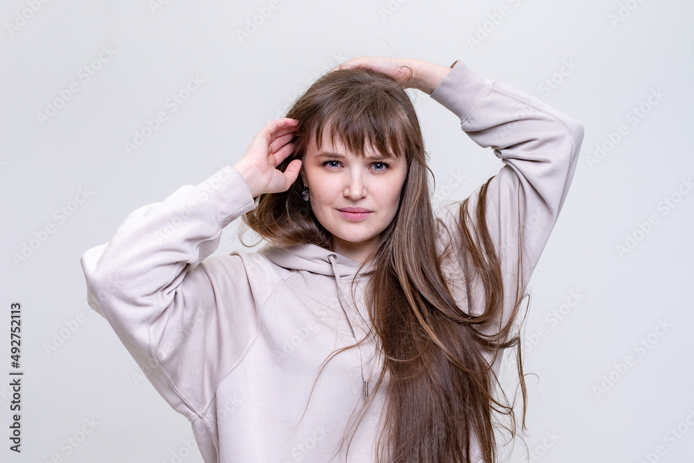 portrait of a pretty blonde girl with long hair in a beige hoodie on a light background portrait of a pretty blonde girl with long hair in a beige hoodie on a light background